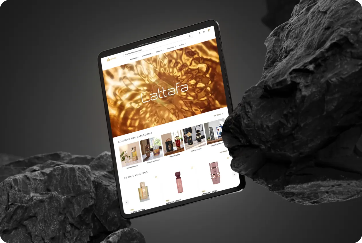 Tablet com a Home da Lattafa, em tons de dourado, apoiado sobre pedras escuras