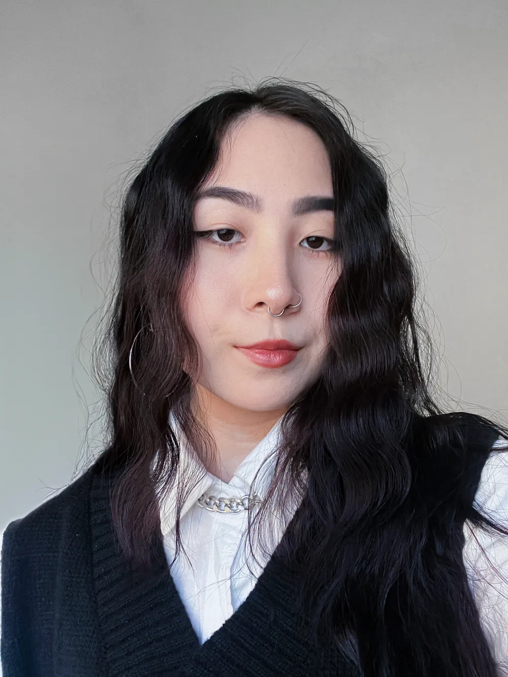 Retrato de Fernanda Lumi Sato, de cabelos longos e escuros, camisa branca e colete preto